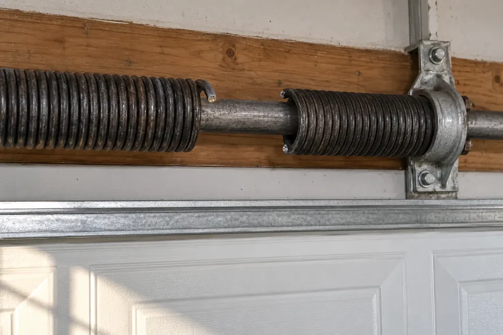 Broken torsion spring with separated coil ends on a steel shaft above a garage door