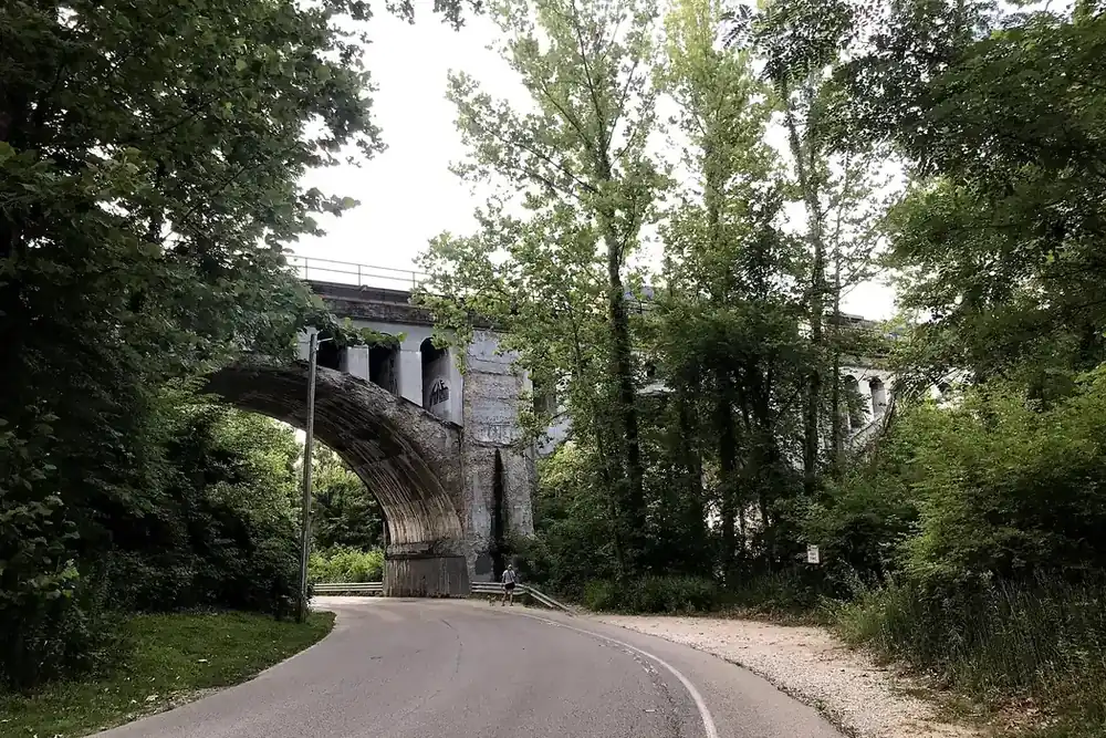 A road curving beneath the stone arch of the Haunted Bridge among trees in Avon, Indiana