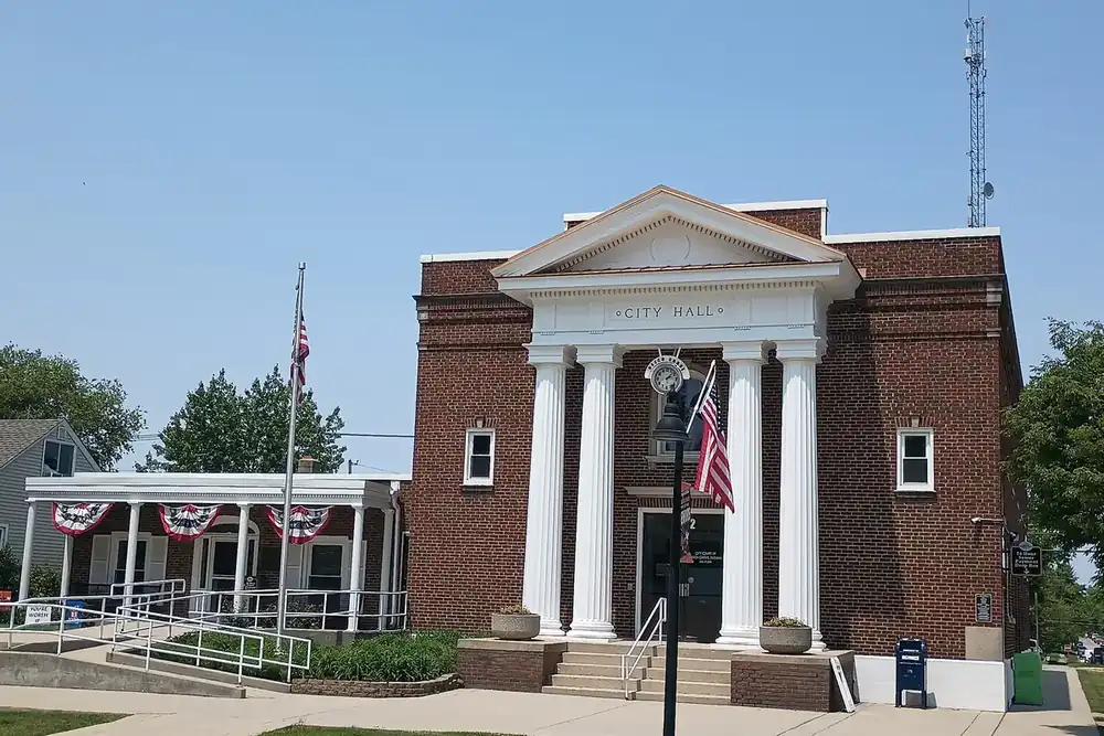 The columned brick Beech Grove City Hall with flag bunting on a sunny day in Indiana