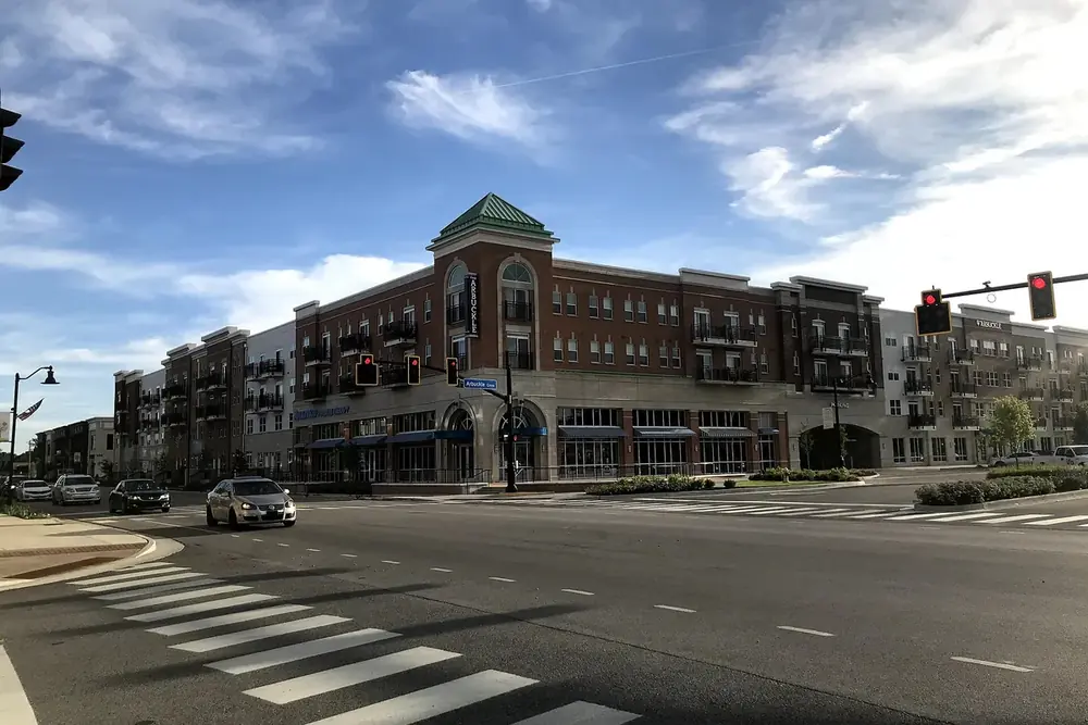 A brick mixed-use building with apartments above shops at a crosswalk in Brownsburg, Indiana