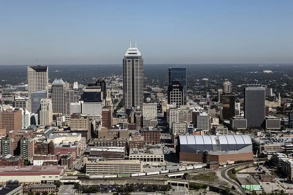 The downtown Indianapolis skyline rising above surrounding neighborhoods on a clear day