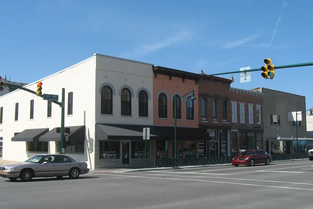 Two-story brick and white storefront buildings at a Main Street intersection in downtown Plainfield, Indiana